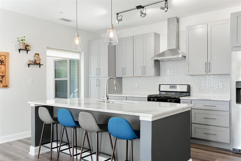 a kitchen with stainless steel appliances a sink a stove a dining table and chairs