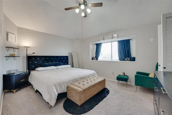 a spacious bedroom with a bed a couch and a chandelier
