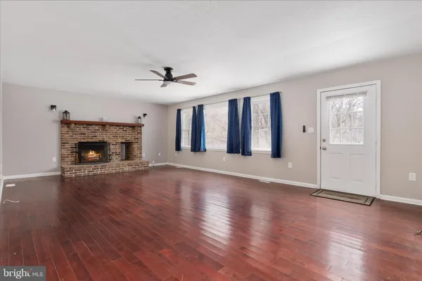 an empty room with fireplace wooden floor and windows