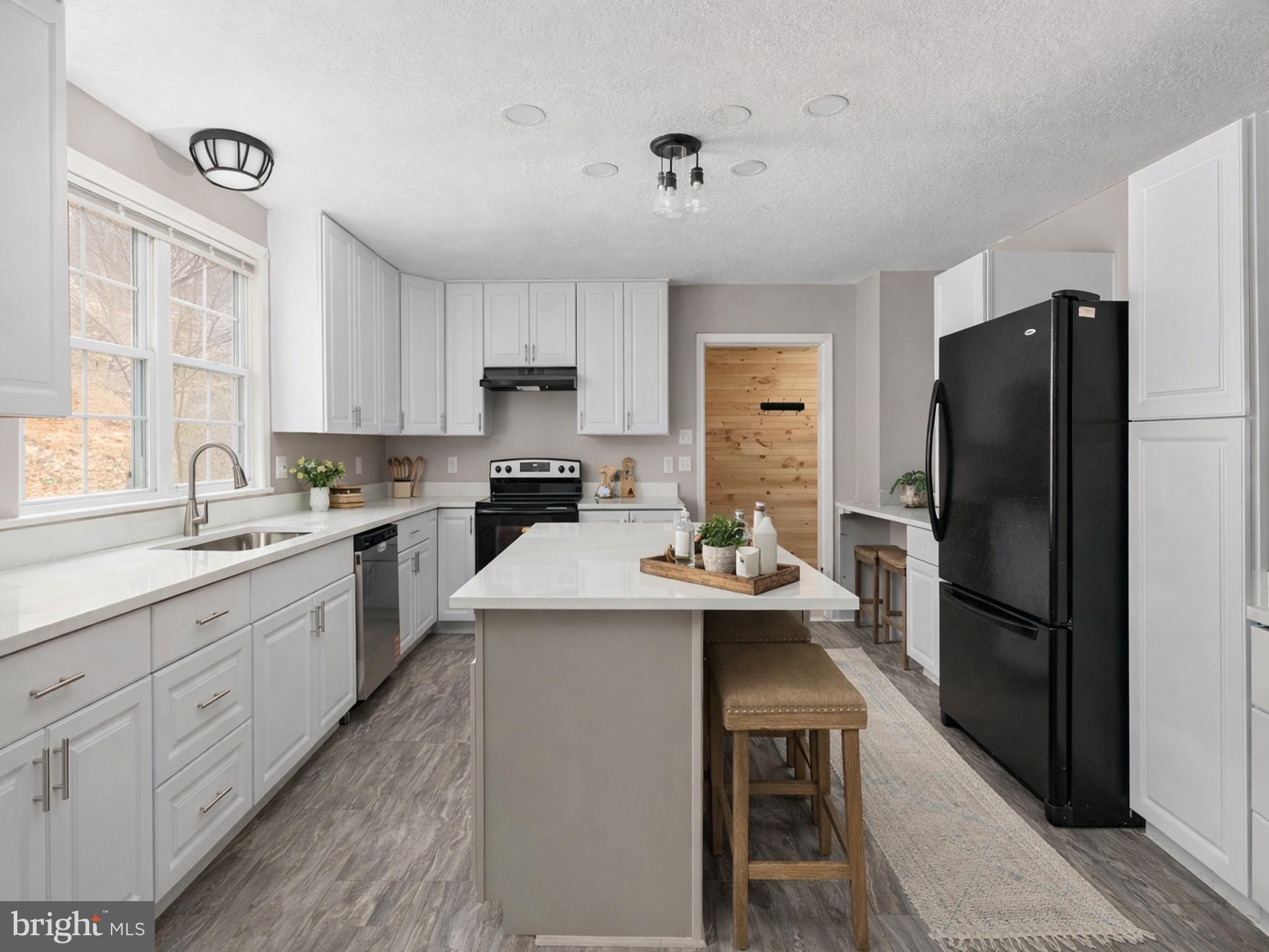 503 Pomeroy Road Front Royal, VA 22630 - Photo 9 of 41 a kitchen with a refrigerator a sink dishwasher a stove and white cabinets with wooden floor