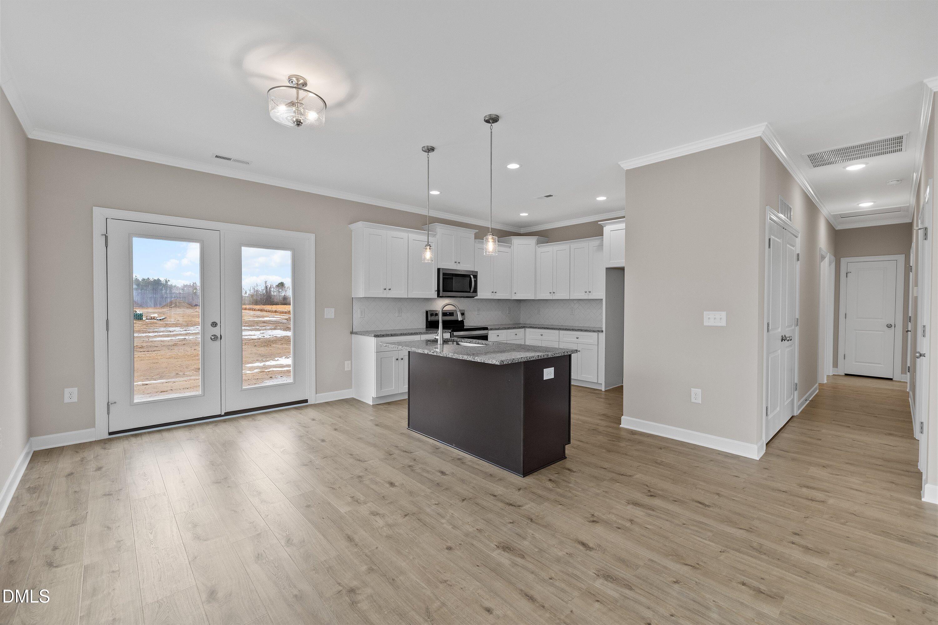 926 Micro Road West Selma, NC 27576 - Photo 16 of 41 a kitchen with stainless steel appliances kitchen island wooden floors and view living room