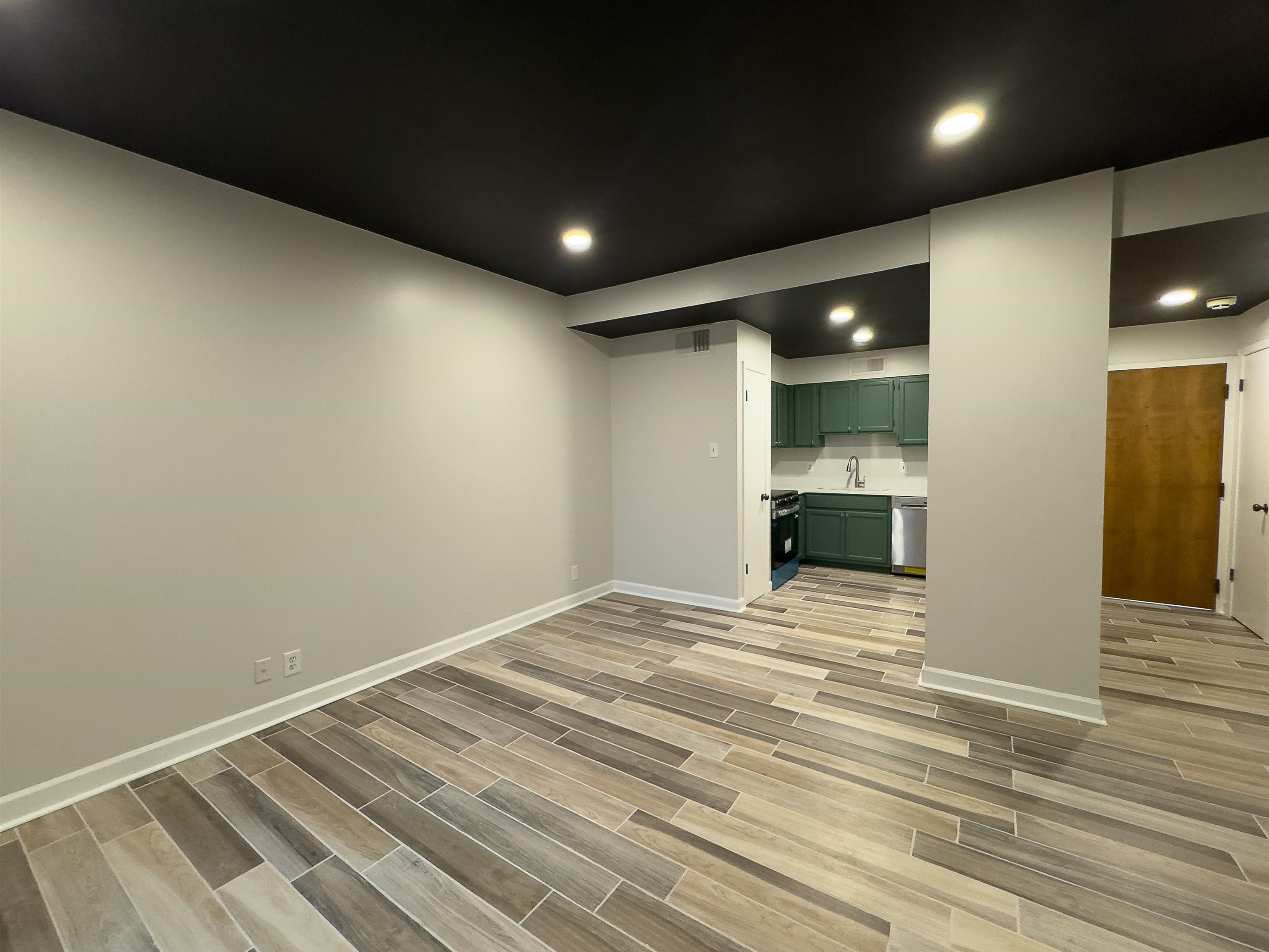 109 North Main Street, Unit 907 Memphis, TN 38103 - Photo 19 of 29 Open-concept living area featuring wood-finish tile flooring, recessed lighting, and a kitchen area with green cabinetry and white countertops