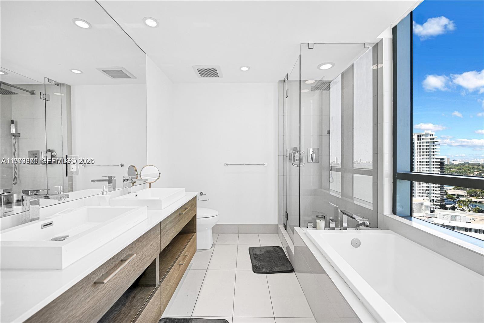 650 Northeast 32nd Street, Unit 2007 Miami, FL 33137 - Photo 12 of 44 a bathroom with a tub double vanity sink and mirror