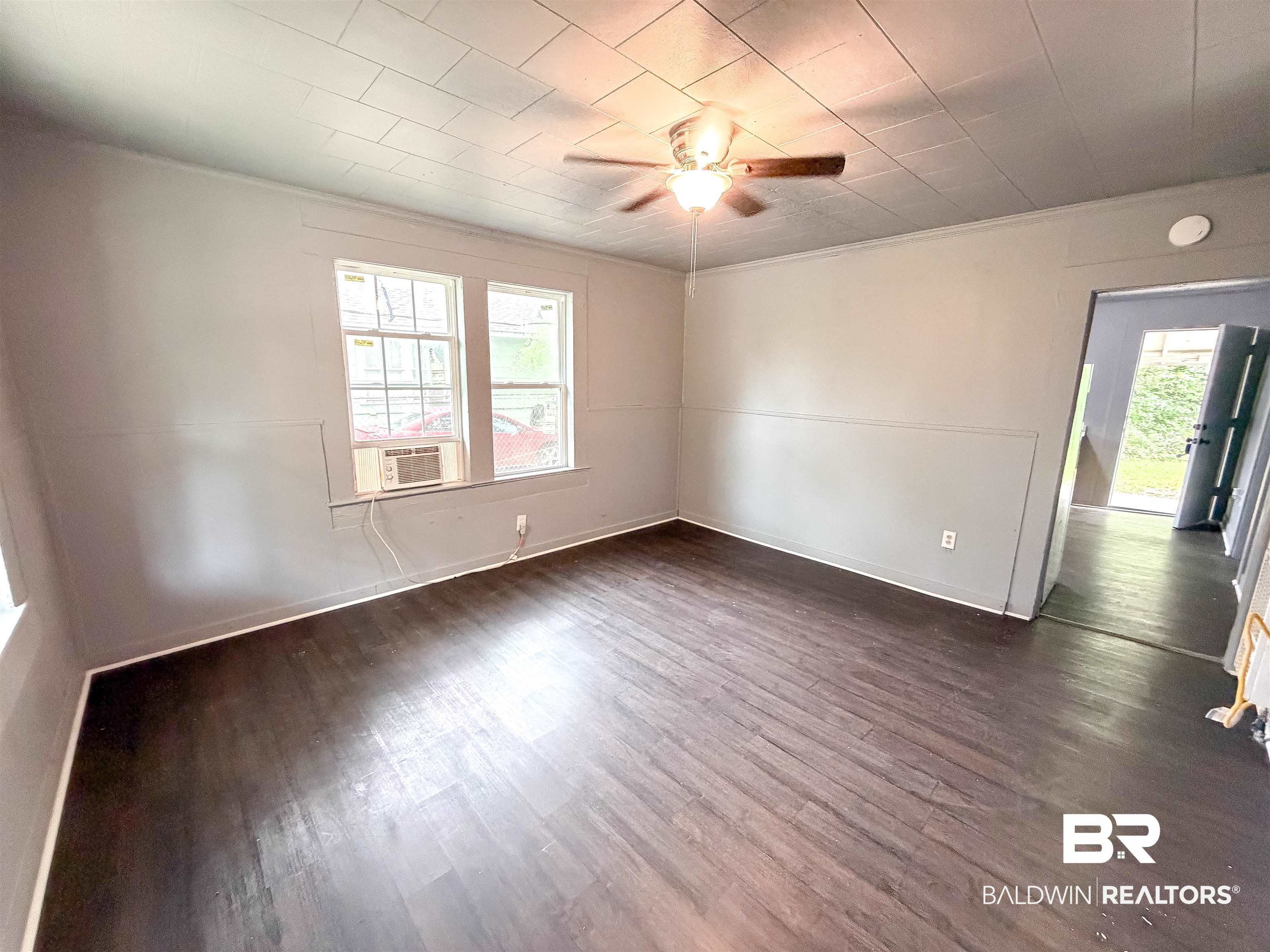 38 Flock Avenue Mobile, AL 36610 - Photo 2 of 27 Spacious room featuring wood-finish flooring, two large windows, and a ceiling fan with integrated lighting