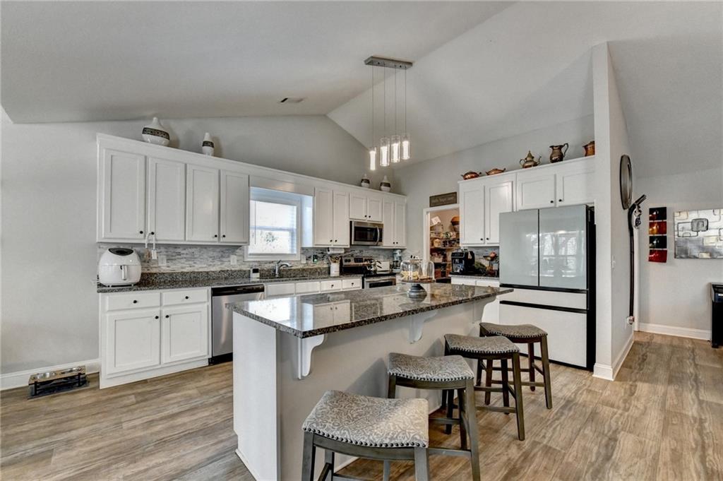 204 Lynn Road Bethlehem, GA 30620 - Photo 2 of 44 a kitchen with stainless steel appliances kitchen island granite countertop a table chairs cabinets and wooden floor