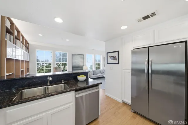a kitchen with a sink white cabinets and black appliances