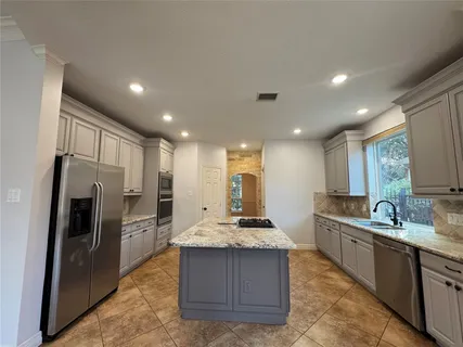 a kitchen with kitchen island granite countertop a sink a refrigerator and a stove