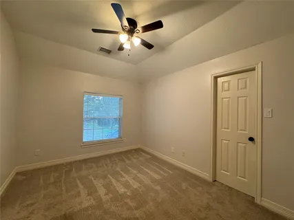 an empty room with a chandelier fan and windows