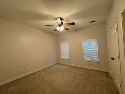 an empty room with chandelier fan and windows