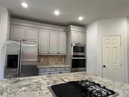 a kitchen with granite countertop a refrigerator and a stove top oven