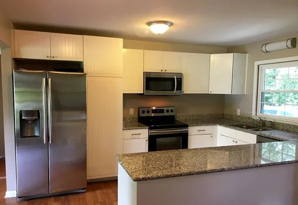 a kitchen with granite countertop a refrigerator and a sink