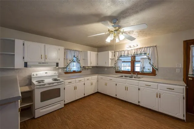 a kitchen with granite countertop white cabinets and white stainless steel appliances