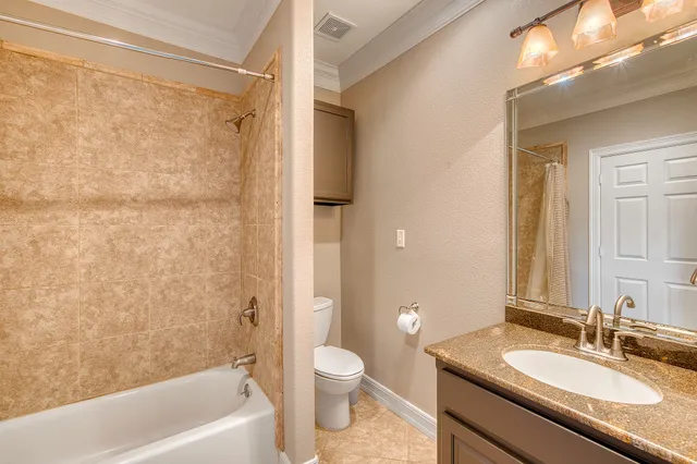 a bathroom with a granite countertop sink a toilet and shower