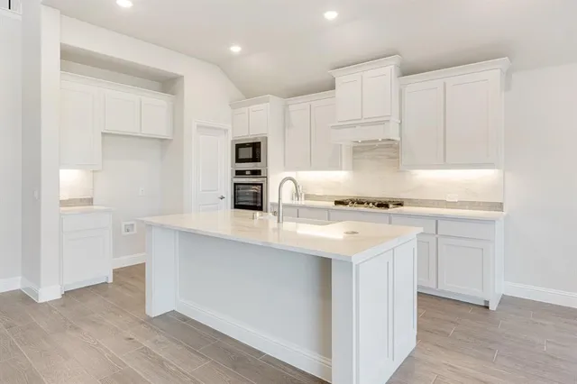 a kitchen with kitchen island a sink a stove a refrigerator and white cabinets
