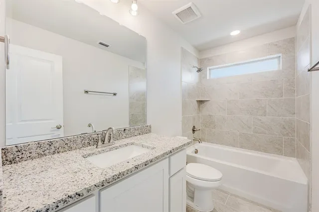 a bathroom with a granite countertop sink a toilet and bathtub