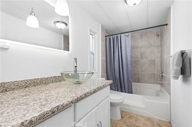 a bathroom with a granite countertop sink a toilet and bathtub
