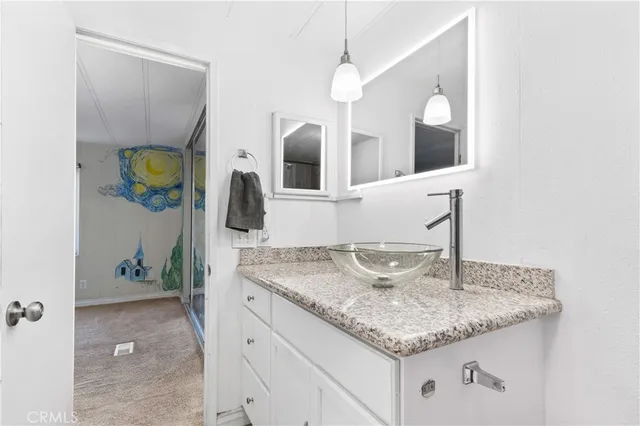 a bathroom with a granite countertop sink and a mirror