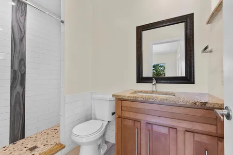 a bathroom with a granite countertop toilet sink and mirror