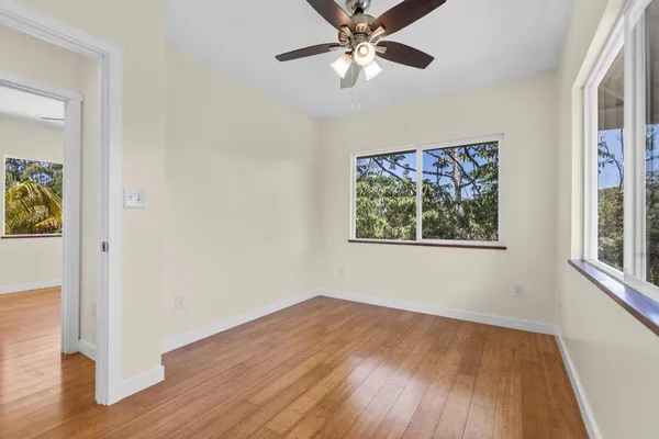 a view of empty room with wooden floor and fan