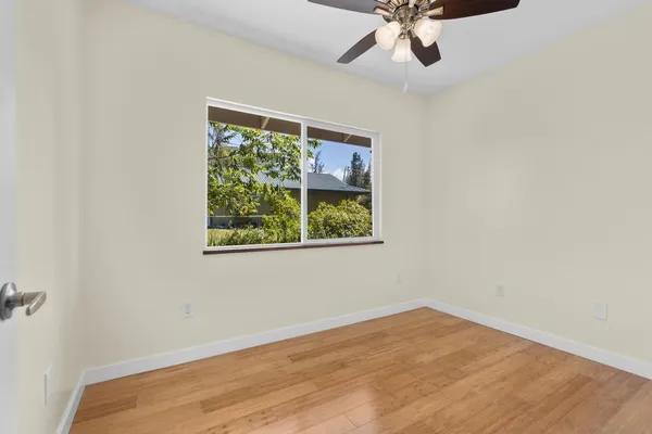 an empty room with a window and a ceiling fan