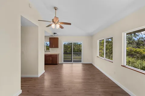 a view of an empty room with a window and wooden floor
