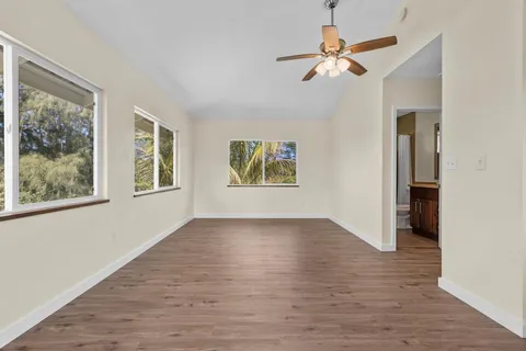 a view of an empty room with a window and a chandelier fan