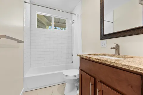 a bathroom with a granite countertop sink toilet a mirror and bathtub