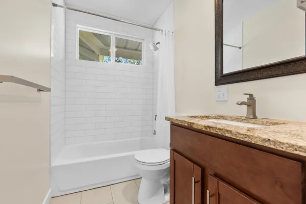 a bathroom with a granite countertop sink toilet a mirror and bathtub