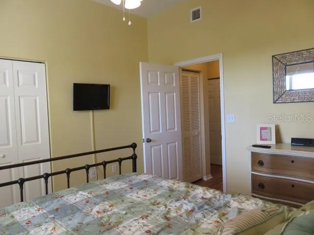 a bedroom with a bed and a flat tv screen on dresser