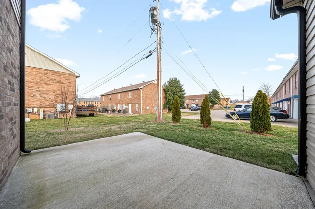 a view of a house with a big yard potted plants and palm trees