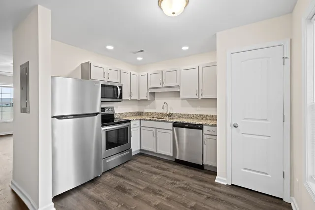 a kitchen with cabinets stainless steel appliances and wooden floor