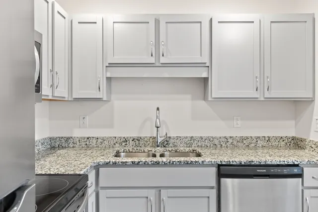 a kitchen with granite countertop stainless steel appliances white cabinets and a sink
