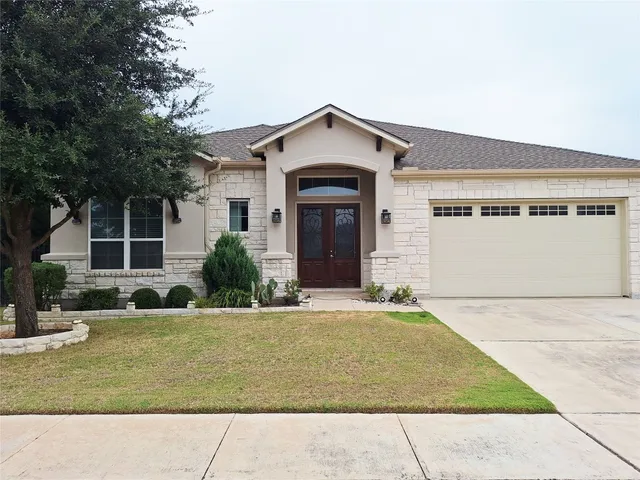 a view of a house with a yard and large tree