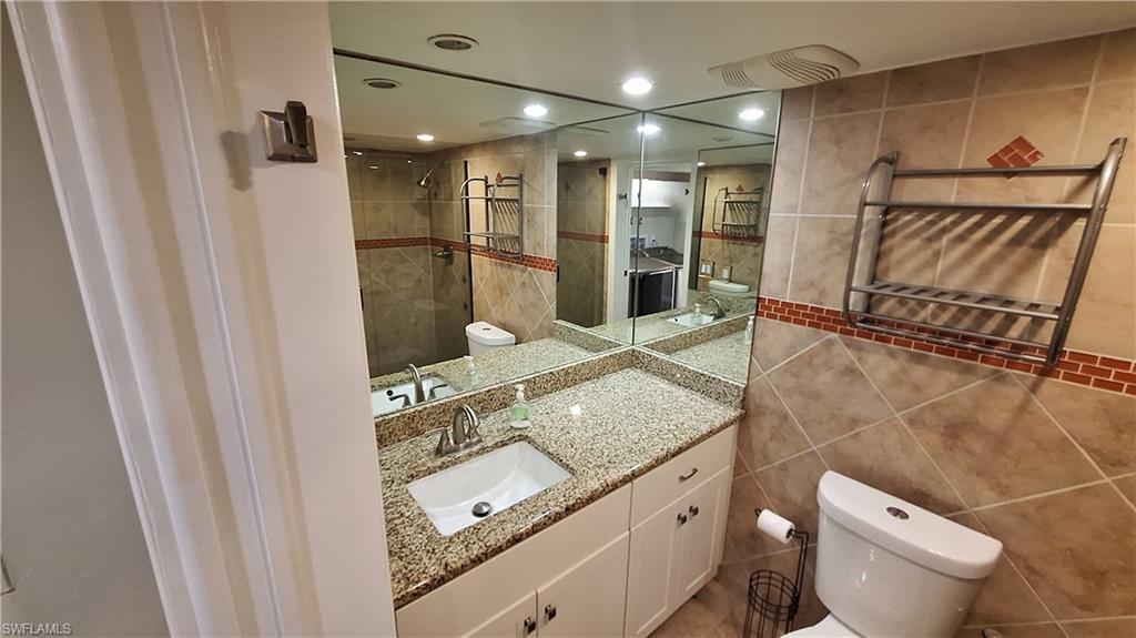 910 Vanderbilt Beach Road, Unit 416E Naples, FL 34108 - Photo 13 of 16 a bathroom with a granite countertop sink and a mirror