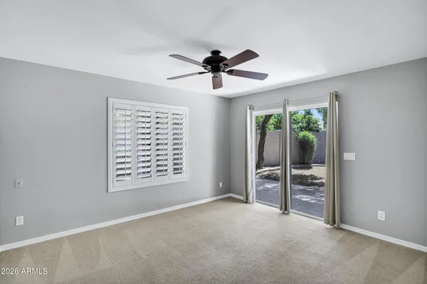 an empty room with a window and a chandelier fan
