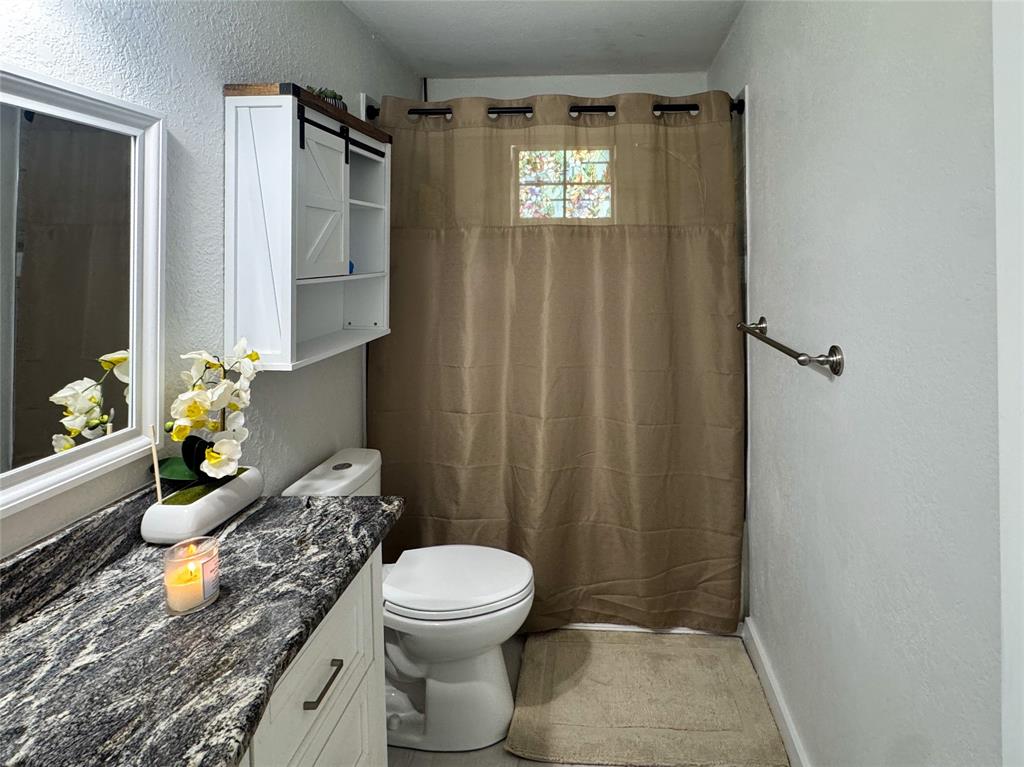 3206 Mitchell Street Greenville, TX 75402 - Photo 15 of 24 a bathroom with a granite countertop sink and a toilet