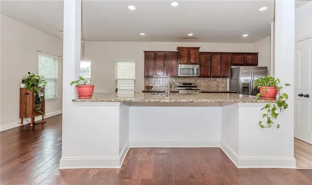 a kitchen with stainless steel appliances granite countertop a refrigerator sink and white cabinets