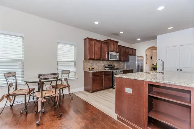 a kitchen with kitchen island granite countertop wooden floors and stainless steel appliances