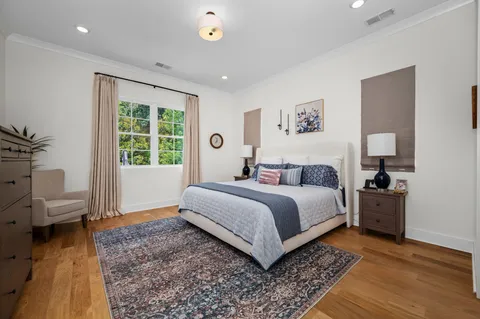 a spacious bedroom with a bed and wooden floor