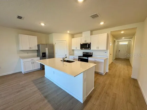 a large kitchen with stainless steel appliances a sink a stove top oven a counter space and cabinets