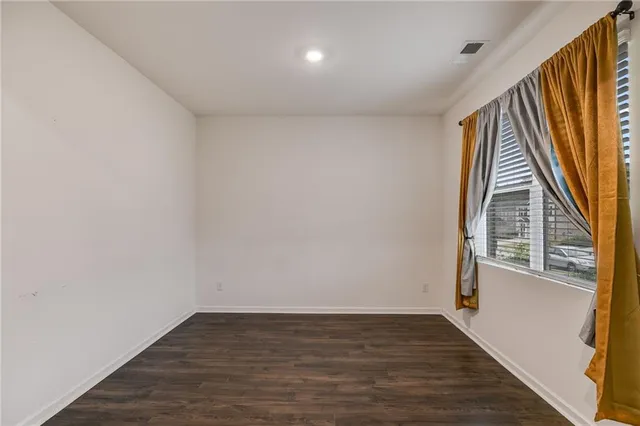 a view of an empty room with wooden floor and stairs