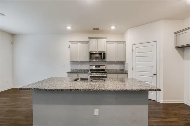 a kitchen with granite countertop white cabinets and refrigerator