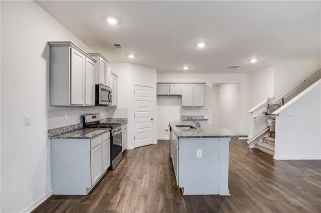 a kitchen with stainless steel appliances granite countertop wooden cabinets sink and stove