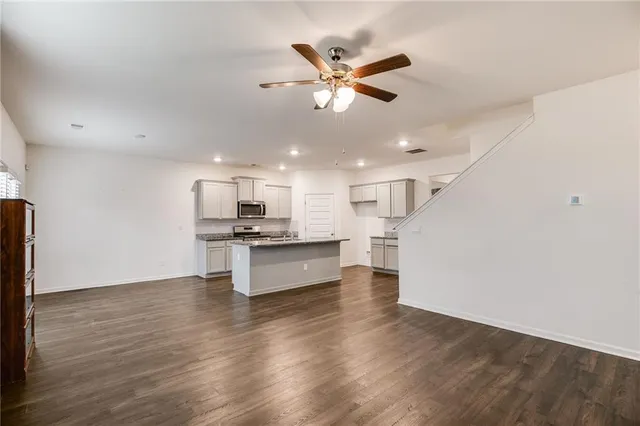 a living room with stainless steel appliances kitchen island hardwood floor and a sink