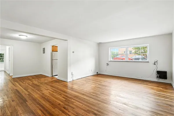 a view of an empty room with wooden floor and a window