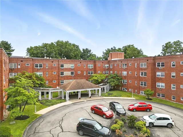 a front view of a building with cars parked