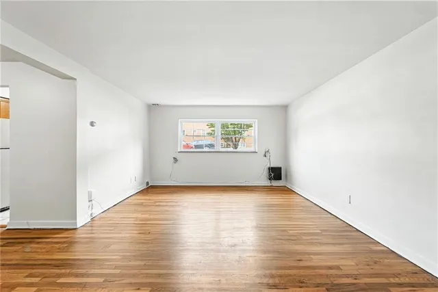 a view of an empty room with a window and wooden floor