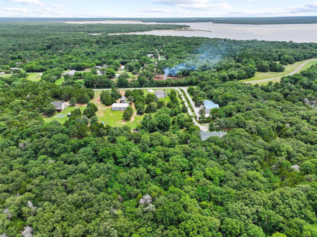 207 Paradise Park Road Pottsboro, TX 75076 - Photo 16 of 28 Expansive wooded property featuring a lake in the background, multiple residential structures, and established roadways