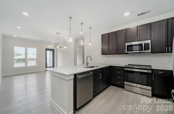 a kitchen with stainless steel appliances granite countertop wooden cabinets a sink a stove a oven and dishwasher with wooden floor