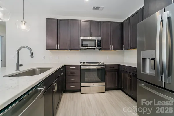 a kitchen with granite countertop a refrigerator and a stove top oven